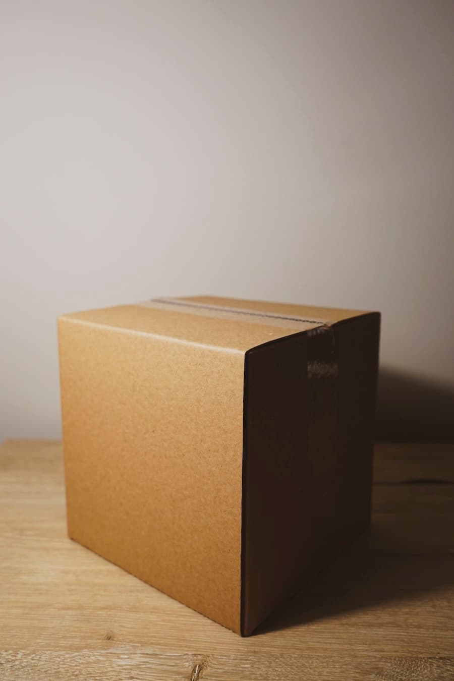 A single unbranded kraft carton on a wooden surface